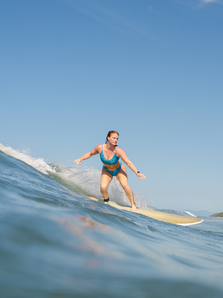 a women surfing while wearing a blue tropical print surf bikini